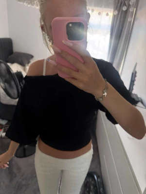 Svart offshoulder topp från Nelly - Trendig svart offshoulder topp från Nelly i storlek XXS. Toppen är croppad och har en ribbad struktur som ger en snygg effekt. Perfekt för dig som gillar en stilren och modern look.