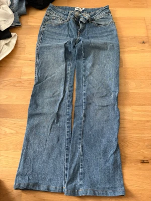 Blå raka jeans med låg midja  - Ett par klassiska blå jeans med raka ben och låg midja. Jeansen har fem fickor, bälteshällor och stängs med knapp och dragkedja. Perfekta för en avslappnad och trendig look. De var även lite långa för mig så jag sydde upp de.