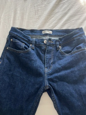 Mörkblå bootcut jeans - Säljer ett par mörkblå bootcut jeans i klassisk femficksmodell. Jeansen har kontrastsömmar och är tillverkade i ett mjukt denimtyg. Perfekta för dig som gillar en retroinspirerad look med utsvängda ben.