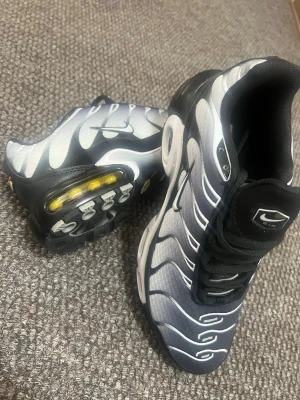 Nike Air Max Plus svart/vit strl: 42 - Nike Air Max Plus sneakers i svart och vitt med ikoniska vågformade detaljer och synlig Air-enhet i sulan. 