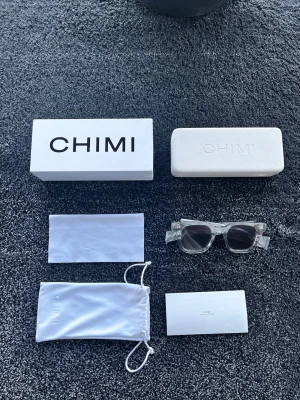 CHIMI 04 - Snygga transparenta solglasögon från CHIMI med fyrkantig form och mörka linser. Kommer med originalförpackning, hårt fodral, putsduk och tygpåse. Perfekta för dig som vill ha en clean och modern look. 9/10 Riktigt bra skick men någon liten repa finns säkert, storlek ONESIZE. Pris går att diskutera ✅