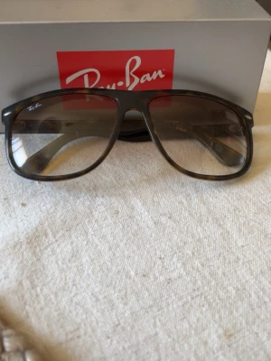 Ray-Ban boyfriend - Snygga solglasögon från Ray-Ban med brunmelerad båge och stora, fyrkantiga glas. Klassisk modell med diskret logga på linsen. Perfekta för att lyfta din stil under soliga dagar.