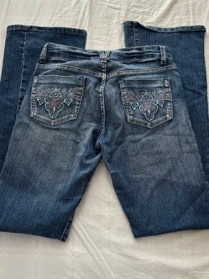 Low waist vintage jeans - Marinblå jeans med skit snygga detaljer på bakfickorna 🤩Köpta secondhand och aldrig själv använt de. Tecken på användning finns från tidigare ägare.