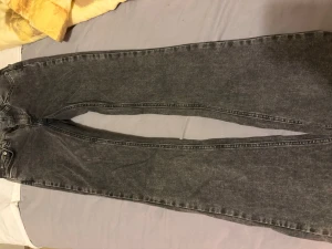 Svarta raka jeans med hög midja - Säljer ett par svarta raka jeans med hög midja och klassiska fem fickor. Jeansen har en tvättad look och raka ben som ger en avslappnad vibe. Passar perfekt till sneakers eller boots och är gjorda i ett robust denimtyg.
