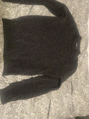 Mörkgrå stickad tröja Dressmann - Mysig mörkgrå stickad tröja från Dressmann i storlek S. Tröjan har rund halsringning, långa ärmar och ribbade muddar vid ärmslut och nederkant. Perfekt för kyliga dagar och enkel att matcha med olika outfits.