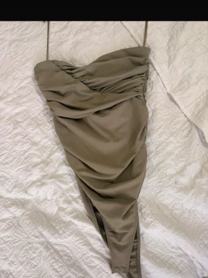 Khaki/grön body från Zara - Trendig beige kortklänning med omlottdesign och tunna axelband. Klänningen har draperade detaljer upptill och en snygg slits framtill. Perfekt för dig som gillar stilrena och moderna plagg.