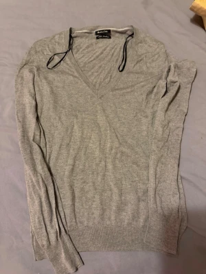 Grå V-ringad tröja Massimo Dutti - Snygg grå stickad tröja från Massimo Dutti i storlek M. Tröjan har V-ringning och är tillverkad i en mjuk blandning av silke och kashmir. Perfekt för dig som gillar stilrena och bekväma plagg med lång ärm och ribbade muddar.