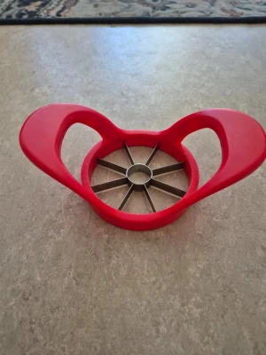 Röd äppeldelare med handtag - Praktisk äppeldelare i röd plast med två stora handtag och åtta vassa blad i metall. Perfekt för att snabbt och enkelt dela äpplen i lika stora klyftor. Smidig att använda i köket och enkel att rengöra.