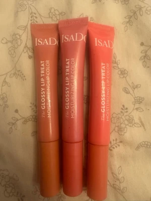 Isadora Glossy Lip Treat trio - Säljer tre Isadora Glossy Lip Treat läppglans i färgerna Pearly Nougat, Pink Pearl och Pink Punch. Tubformat med skruvkork och återfuktande formula. Färgerna går i nude, ljusrosa och korallrosa toner. Perfekt för dig som vill ha glansiga och mjuka läppar. 