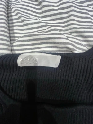 Svart ribbstickad tröja från Samsøe Samsøe - Snygg svart ribbstickad tröja från Samsøe Samsøe i storlek S. Tröjan har lång ärm, figurnära passform och rund halsringning. Perfekt att styla med jeans eller kjol för en trendig look.