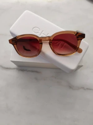 Bruna solglasögon från Chimi - Snygga solglasögon från Chimi med transparent brun båge och bruna tonade glas. Modellen har en klassisk, något rundad form och är tillverkad i syntetmaterial. Perfekta för att lyfta din stil med en cool touch. Hämtas i centrala Stockholm eller skickas.