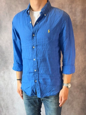 Blå Ralph Lauren Linneskjorta - Stl M, Slim fit - Riktig snygg Ralph Lauren Linneskjorta i blått, perfekt till sommaren! 🏖️🌊 | Mycket bra skick: 9,2/10, utan defekter  | Stl: M |  Modellen är 177cm och väger 74kg | Billigare pris vid köp av bundle 😉Hör av dig vid frågor // Galgen 🫡 