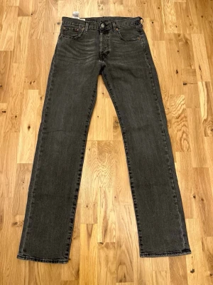 Svarta raka jeans från Levi's - Snygga svarta jeans från Levi's med klassisk femficksdesign och raka ben. Jeansen har en diskret tvättad look och är tillverkade i bomull. Perfekta för en stilren och avslappnad outfit.