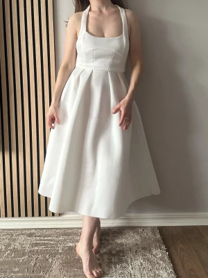 ASOS Vit långklänning med breda axelband - Stilren vit långklänning med breda axelband och markerad midja. Klänningen har en utsvängd kjol och är ärmlös med fyrkantig ringning. Perfekt för dig som gillar minimalistisk och elegant stil. Det är storlek 32. 