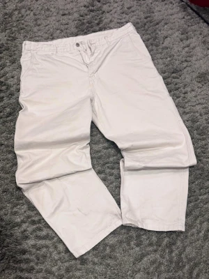 Vita bomullsshorts med normal passform - Säljer ett par vita shorts i bomull med klassisk design och normal passform. De har bälteshällor, knapp och dragkedja framtill samt raka ben. Perfekta för varma dagar och enkel att matcha med olika toppar.