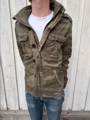 Abercrombie & Fitch Camo Fieldjacket  - En mycket trevlig fieldjacket från Abercrombie & Fitch i ett extremt snyggt camo mönster! Modellen är 178 cm och väger 68 kg. Hör av dig vid frågor! 