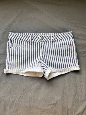 Randiga shorts - Snygga blåvit-randiga shorts  klassisk femficksdesign och råa kanter. Shortsen har låg midja och är perfekta för varma sommardagar. Midjemått 78cm