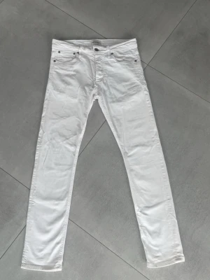 Vita jeans Jack and Jones  - Tjenaret! Säljer ett par vita slim jeans med klassisk femficksdesign och normalhög midja. Jeansen har slim passform och stängs med ungefär 5 knappar. Perfekta till en clean och fräsch look. Materialet är troligtvis bomull med lite stretch. Märket är Jack and Jones och modell är slim fit glenn. Storlek 31/32, dom är för små i midjan för mig men passar bra i längden och jag är 183cm och väger 72! Skick 8/10-lite gula fläckar på bakfickan men inget som syns! Hör av dig vid frågor! //premium fashion