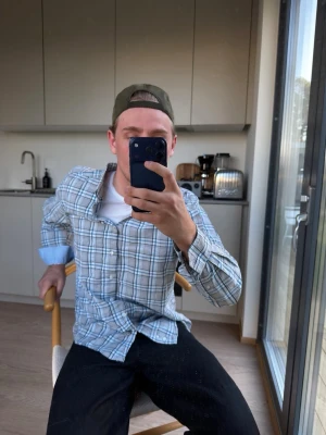 Blåvit rutig skjorta med knappar - Säljer en klassisk blåvit rutig skjorta med knäppning framtill och lång ärm. Skjortan har en avslappnad passform och är tillverkad i mjuk bomull, perfekt för en chill och stilren look. L passar M