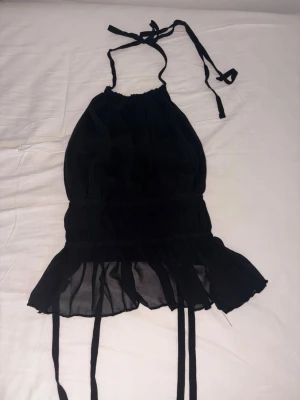 Svart halterneck topp - Trendig svart halterneck topp, den är i nytt skick då jag aldrig använt den.