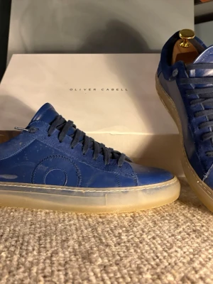 Oliver cabell low 1 marin blå - Snygga low 1’s från Oliver Cabell. Skorna har ovandel i skinn och mocka, samt mörkblå snörning. Yttersulan är transparent. Perfekt för dig som gillar stilrena och moderna sneakers nu till sommarn. Skorna är i storlek 42 men jag skulle säga att de passar 43 också