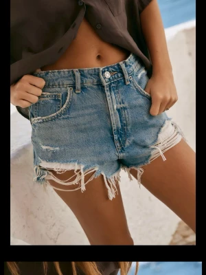 Blå denimshorts med slitna detaljer Zara - Trendiga blå denimshorts med hög midja och råa, slitna kanter. Shortsen har klassisk femficksdesign, dragkedja och knapp framtill samt tydliga slitningar. Köpta på Zara i höstas men passar ej mig. Storlek 38