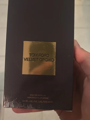 Tom Ford Velvet Orchid EdP 100ml - Tom Ford Velvet Orchid Eau de Parfum i en lyxig mörklila kartong med gulddetaljer. Flaskan rymmer 100 ml och doften är känd för sina blommiga och sensuella toner. Perfekt för dig som gillar exklusiva och unika parfymer.