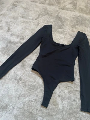 Svart långärmad body från Zara -  svart body från Zara med lång ärm och djup rundad urringning.