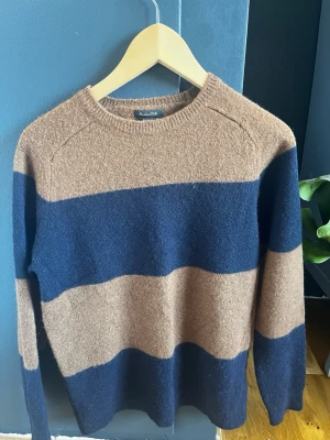 Randig stickad tröja från Massimo Dutti - Stickad tröja från Massimo Dutti med breda horisontella ränder i mörkblått och brunt. Tröjan har rund halsringning och långa ärmar. Materialet är mjukt och har en äkta stickad känsla. Klassisk och avslappnad stil. OBS! storleken är liten och passar bäst på den som bär S 