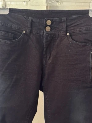 Svarta  jeans från Fransa - Snygga svarta jeans från Fransa med dubbla knappar i midjan och klassisk femficksdesign. Jeansen har en smal passform och är tillverkade i stretchigt denimtyg för extra komfort. Oanvända.