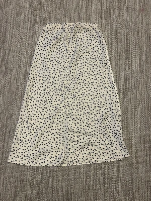 Vit prickig midikjol med knappar - Cremefärgad midikjol med knappar och slits fram. Resår högst upp. Följsam på kroppen