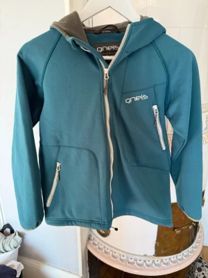 Turkos hoodie från Gneis med dragkedja - Snygg turkos hoodie från Gneis med hel dragkedja och tre fickor med dragkedjor. Mjuk grå fleece på insidan av huvan. Broderad logga på bröstet och bak på huvan. Perfekt för en avslappnad stil.