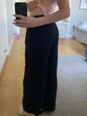 Svarta linnebyxor - Säljer ett par svarta linnebyxor, resår och knytning i midjan. Byxorna har en avslappnad, rak passform och är tillverkade i ett lätt och luftigt linnematerial. Perfekta för en chill och stilren look.