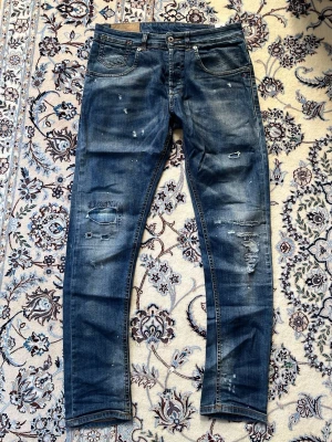 Dondup jeans - Säljer ett par blå jeans med slitningar och hål på både fram- och baksida från märket DONDUP. Jeansen har en klassisk femficksmodell med W29 men passar också W30-31.