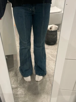 Blå bootcut jeans med låg midja  - Jättesnygga mörkblå jeans från cheap monday med låg midja och i bootcut modellen. Jeansen är oanvända då jag köpte fel storlek och de inte passar mig. Jeansen har en snygg utsvängd passform från knät och ner, vilket ger en retrovibe. Tillverkade i ett mjukt denimtyg som sitter bekvämt. Perfekta till sneakers eller boots för en avslappnad look. Jeansen är perfekta för både finare tillfällen och till vardags och har inga defekter då de är nya. Storleken är 28/30 och har 74 cm i midjemått. 