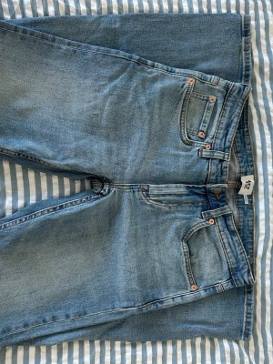 Blå raka jeans  - Snygga blå jeans med klassisk femficksmodell och raka ben. Jeansen har en ljus tvätt och kopparfärgade nitar vid fickorna. Perfekta för en avslappnad och trendig stil. Materialet är mjukt denim i bomull. W32 L32