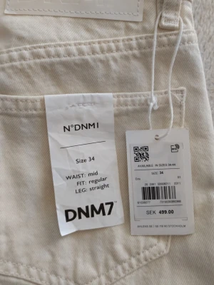 Vita raka jeans från DNM7 - Snygga vita jeans från DNM7 med rak passform och midjehög midja. Jeansen har klassisk femficksdesign och är tillverkade i ett kraftigt denimtyg. Perfekta för en clean och stilren look.