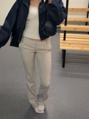 Beiga kostymbyxor med rak passform - Säljer ett par stilrena beiga kostymbyxor med rak passform och normal midja. Byxorna har klassiska pressveck och är tillverkade i ett mjukt, vävt material som ger en clean look. Perfekta att matcha med crop top eller hoodie för en trendig vibe. I modellen tall❤️