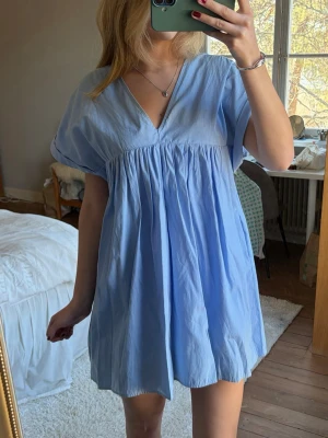 Ljusblå kort klänning med v-ringning - Supersöt ljusblå kort klänning med v-ringning. Klänningen har inbyggda shorts under vilket gör det skönt och avslappnat att röra sig