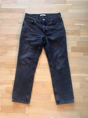 Svarta raka jeans från Zara - Säljer ett par svarta jeans från Zara med rak passform och klassisk femficksdesign. Jeansen har knappgylf. 
