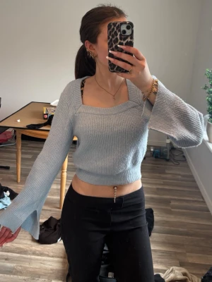 Ljusblå croppad stickad tröja - Trendig ljusblå croppad stickad tröja med vida ärmar och ribbade muddar. Tröjan har en fyrkantig ringning och skulle säga att storleken är xs/s