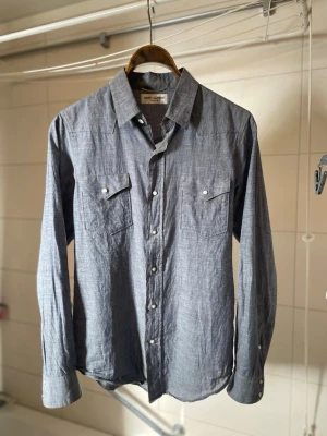 Saint Laurent skjorta (2013) - Sample indigo Saint laurent western skjorta ifrån 2013-14. Se sista bild för sample tag. Grå, ljus-blå i färgen. Passar S. Skriv gjärna för frågor