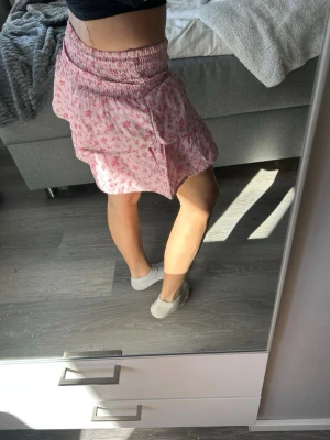 Rosa blommig kortkjol med volang - Supersöt rosa kortkjol med små blommor och volangkant 💞