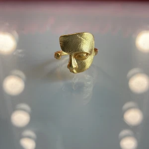 Guldfärgad ring med ansiktsmotiv - Unik guldfärgad ring med ett coolt ansiktsmotiv framtill. Ringen har en öppen design och är tillverkad i metall med matt finish. Perfekt för dig som gillar statement-smycken och vill sticka ut med din stil.
