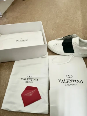 Valentino Garavani - Säljer ett par vita sneakers från Valentino Garavani med svart detalj. Väldigt fint skick de ser nästan helt nya ut och man märker knappt att de är använda.  Allt original följer med (box, dust bag och påse). Hör gärna av dig vid intresse, och skriv privat om du vill ha fler bilder eller mer info 😊