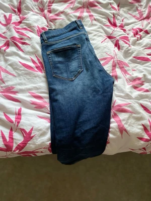 Mörkblå Levi's jeans med raka ben - Säljer ett par klassiska mörkblå jeans från Levi's med raka ben och femficksmodell. Jeansen har snygga kontrastsömmar och en ikonisk läderpatch bak i midjan. Perfekta till vardagslooken och passar till det mesta. Materialet är slitstarkt denim i bomull.
