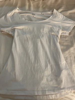 Vit basic t-shirt från 157 - En enkel vit t-shirt från 157 med rund halsringning och korta ärmar. Tillverkad i mjuk bomull som känns skön mot huden. Perfekt att matcha med jeans eller shorts för en clean och avslappnad look.