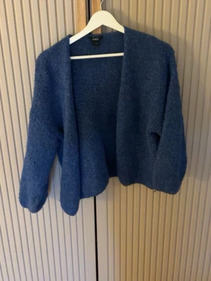 Blå mysig kofta från Lindex - Säljer en blå, fluffig och öppen kofta från Lindex i storlek XS/S. Koftan har lång ärm och en avslappnad passform, perfekt att slänga på sig över en t-shirt eller topp. Materialet är mjukt och ger en riktigt cozy känsla. Nopprig då den är tvättad flertal gånger, annars bra skick 