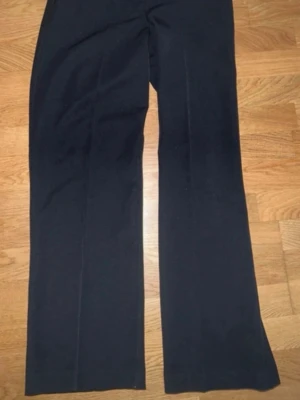 Svarta kostymbyxor från BikBok - Stilrena svarta kostymbyxor från BikBok med raka ben och pressveck. Byxorna har klassisk passform och stängs med knapp och dragkedja. Perfekta för en dressad look. Materialet känns mjukt och följsamt.