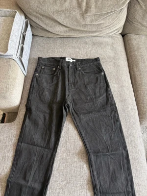 Svarta jeans från 157 New Classic - Svarta raka jeans från 157 New Classic med klassisk femficksdesign och silverfärgade nitar. Jeansen har bälteshällor och knappgylf. Perfekta för en stilren och enkel look.